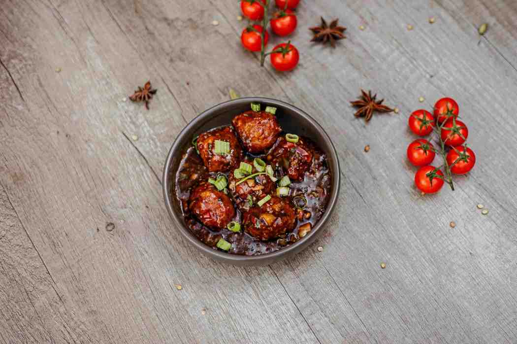 Indo-Chinese manchurian in a dark bowl with spring onions at Bukharaa, Stockport